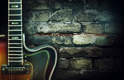 Old vintage jazz guitar on a brick wall background. Copy space ...